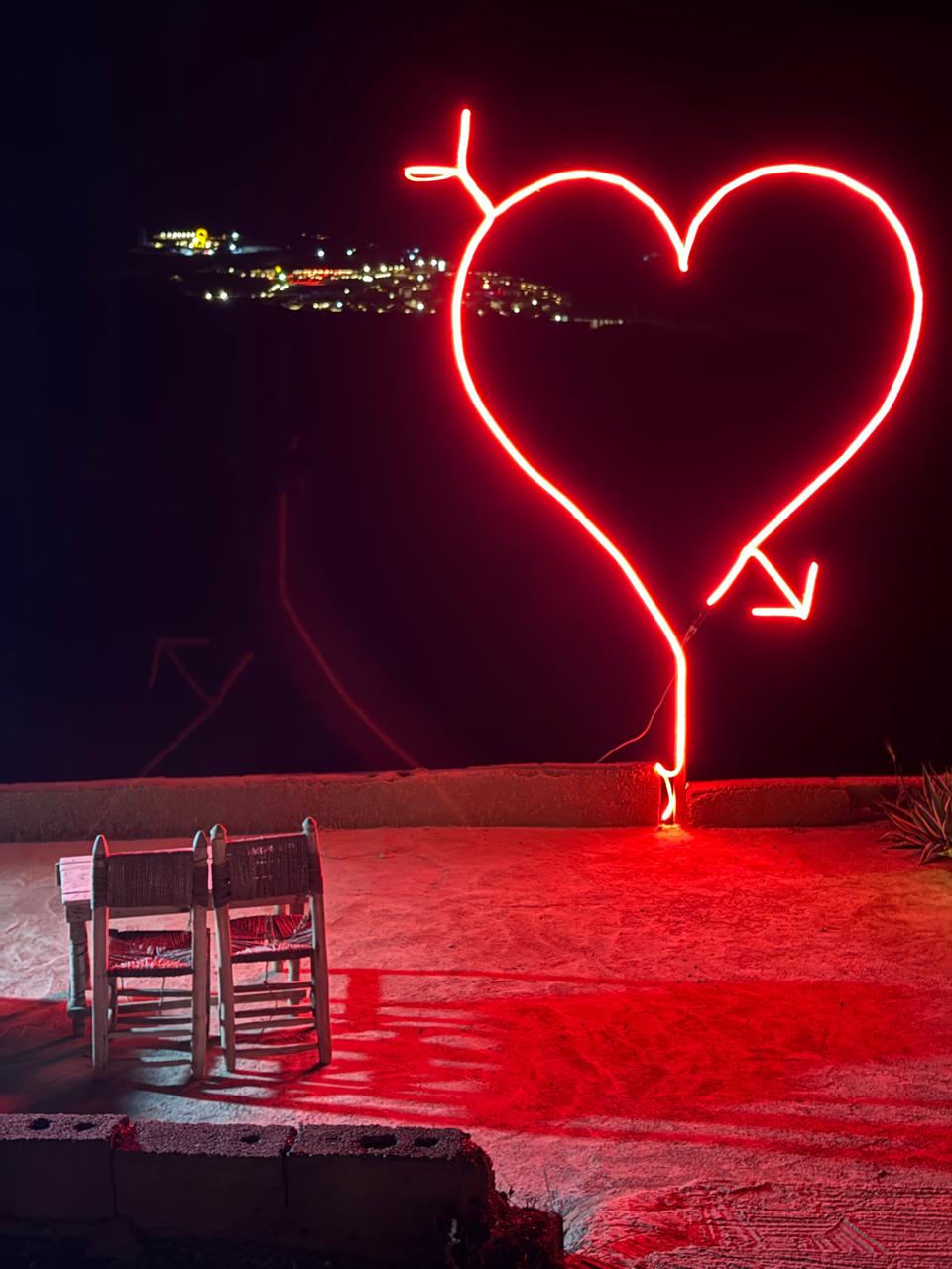 Rooftop neon heart at night Marrakech city view